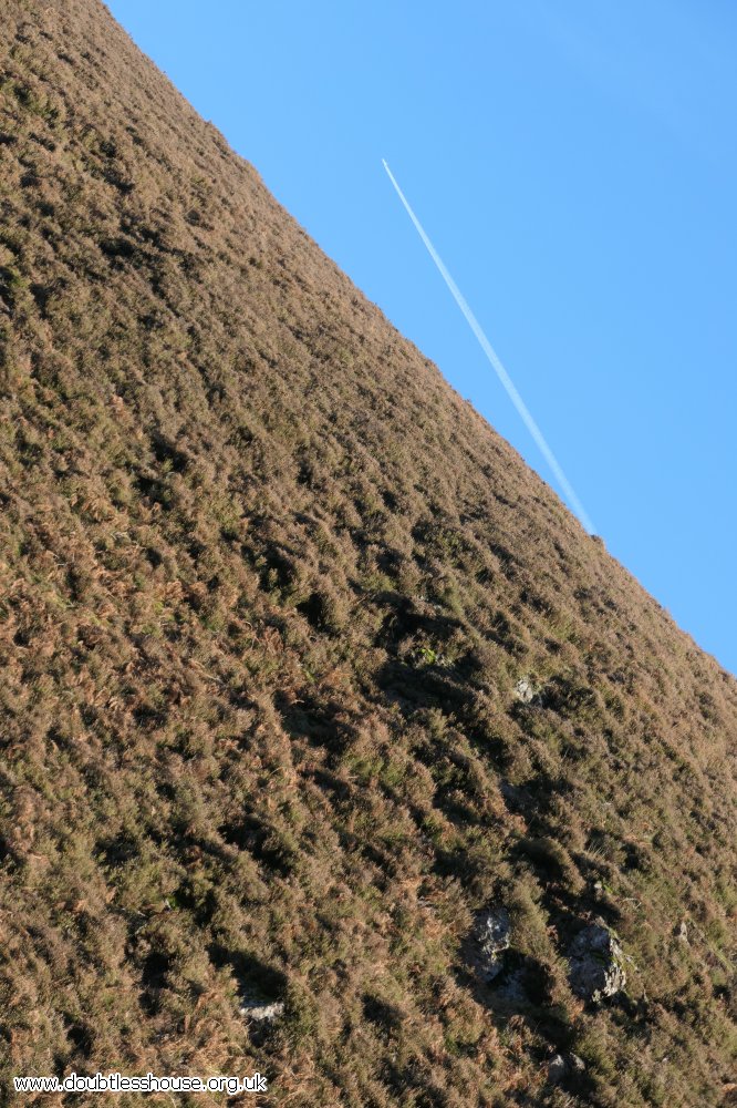 hillside and sky with plane trail