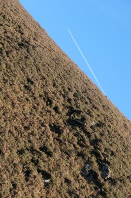 hillside and sky with plane trail